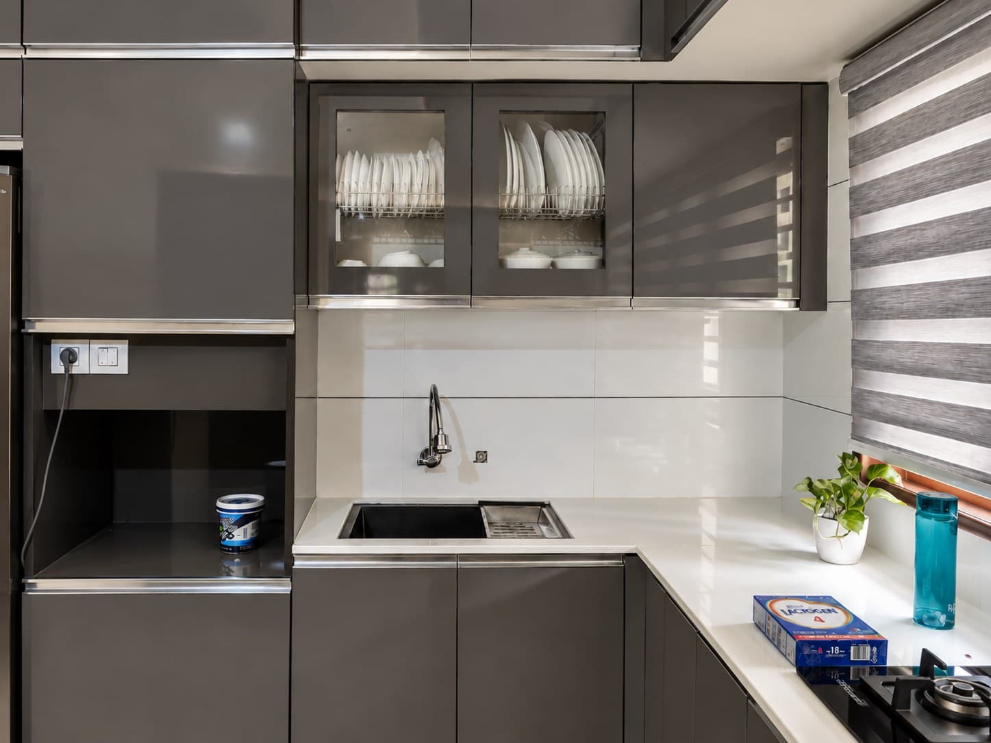 Kitchen detail with charcoal cabinetry, white countertop, sink and warm timber window