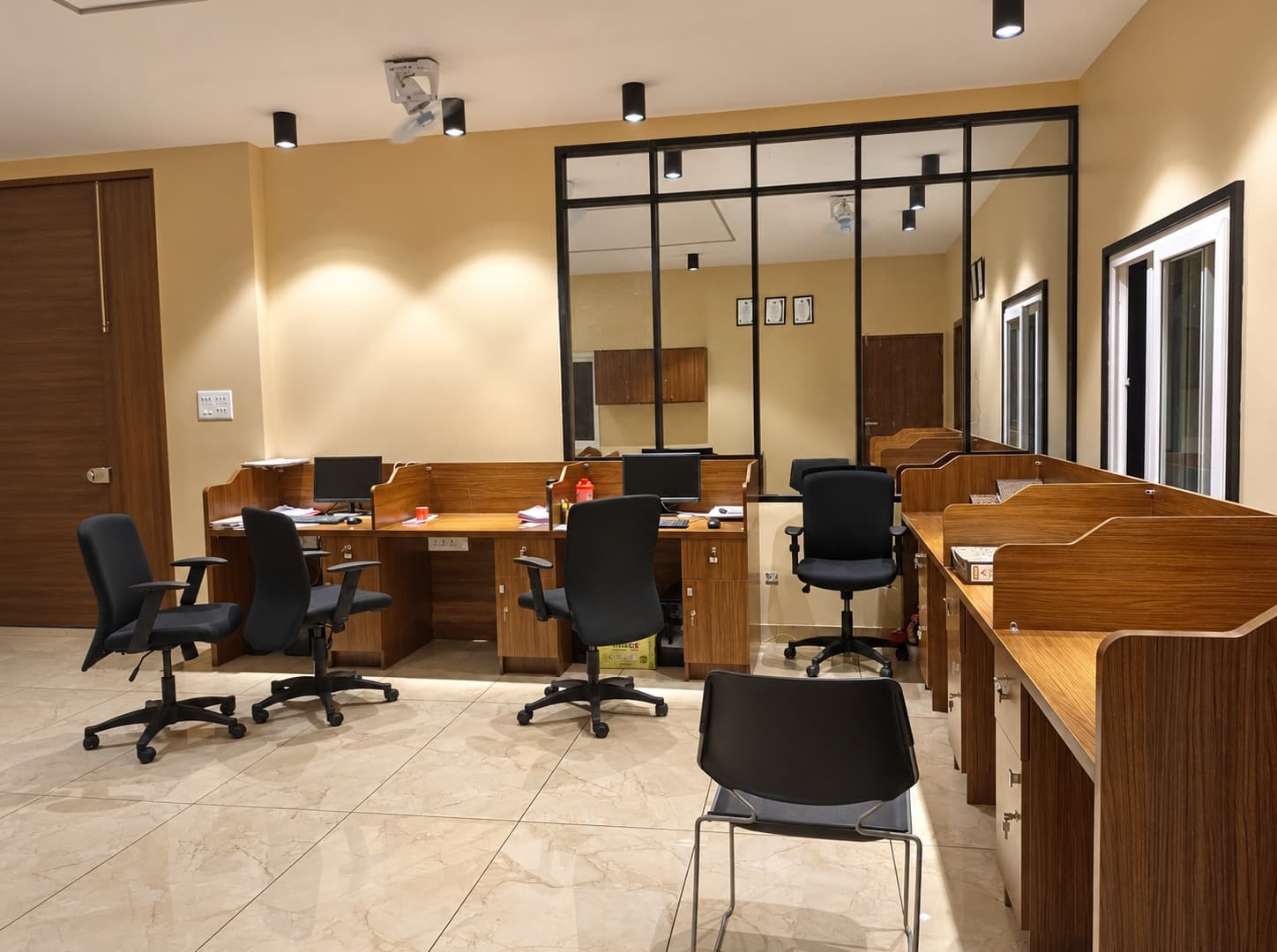 Office workstations at True Froot, with warm timber desks and black-framed glass partitions
